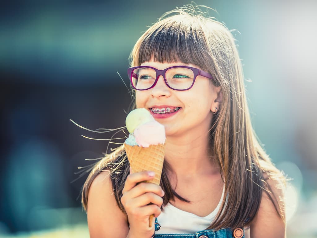 petite fille avec attaches dentaires mangeant une glace